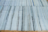 Hand-woven vintage rag rug texture with pastel and neutral stripes, showing central seam.