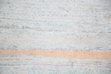 Textured hand woven rag rug in pastel blue, ivory, charcoal, and orange stripes.