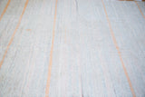Close-up of hand woven recycled linen rag rug with subtle pastel and orange stripes.