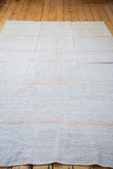 Hand-woven detail of a vintage rag rug, showing pastel ivory and light blue with a peach stripe.