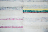 Hand woven mid-century rag rug detail showcasing stitched seam and colorful linen strips.
