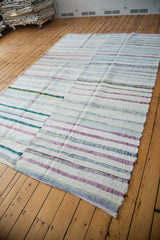 Vintage hand-woven rag rug edge, showing textured pastel and neutral stripes.