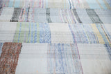 Textured hand-woven rag rug with pastel blue, green, ivory, and charcoal plaid pattern.
