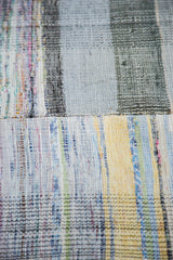 Vintage hand-woven rag rug texture, showing plaid effect with pastel and neutral linen strips.