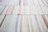 Close-up of vintage hand-woven rag rug showcasing pastel linen stripes and segmented texture.