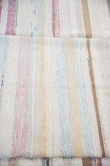 Vintage rag rug with hand woven pastel pink, blue, and ivory striped texture.