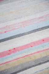 Close-up of hand-woven vintage rag rug texture with pastel stripes and neutral tones.