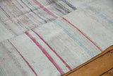 Vintage hand woven rag rug detail, textured ivory with prominent ruby red stripes.