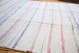 Vintage hand-woven rag rug with textured ivory base and faded pastel pink, blue stripes.