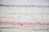 Vintage hand woven rag rug detail, showing textured ivory, red, and charcoal linen strips.