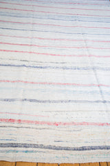 Textural hand-woven vintage rag rug edge with subtle ivory, pastel, and charcoal stripes.