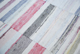 Close-up of hand woven rag rug, textured pastel and neutral recycled linen strips.