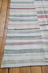 Hand-woven texture and pastel striped patterns on the corner edge of a vintage rag rug.