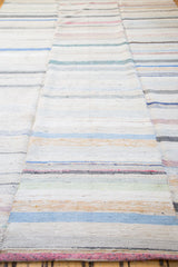 Textured hand woven rag rug featuring ivory, charcoal, and soft pastel stripes.