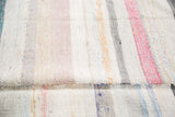 Detail of the hand-woven rag rug's striped texture with pastel and neutral tones.