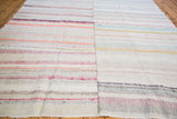 Horizontal stripes of a hand woven rag rug showing pastel and neutral shades.