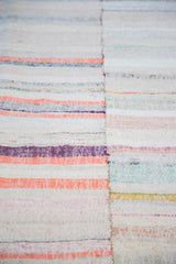Close-up of hand woven vintage rag rug with visible vertical seam and pastel, neutral linen stripes.