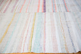 Textured hand woven rag rug with vertical stripes in pastel pink, yellow, and ivory.