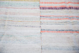Vertical seam and hand-woven texture of a vintage rag rug with pastel, ivory stripes.