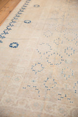 Subtle repeating geometric motifs on worn ivory and blue Khotan carpet pile.
