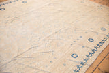 Ivory field with blue repeating medallions and worn pile on a Khotan style carpet.