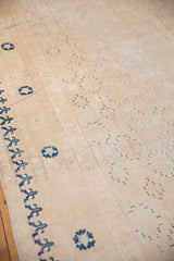 Khotan carpet, showing worn ivory field with repeating blue decorative motifs.