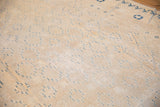 Ivory and blue Khotan style carpet with repeating medallions and a worn aesthetic.