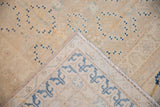 Vintage Khotan carpet corner detail, revealing geometric blue border on ivory with scattered field motifs.