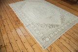 Corner of vintage Oushak carpet with ivory field, curvilinear platinum beige border, and fringe.