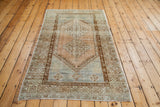 Geometric border and distressed pile of an Oushak rug in blue and terra cotta.