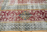 Whimsical burgundy florals and deep green geometric patterns on a decorative distressed Oushak rug.