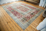 Distressed Oushak carpet corner with wide burgundy floral border and geometric patterns.