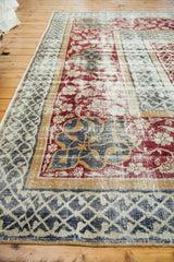 Distressed Oushak rug with wide geometric border, faded burgundy, dark green, and tan designs.