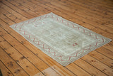 Distressed Oushak rug showcasing faded platinum, light sage, and red zigzag border.