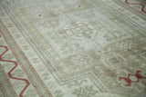 Distressed Oushak rug detail showing muted platinum and sage geometric motifs with red tribal accents.