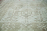 Vintage distressed Oushak rug pile texture with muted platinum and sage motifs.