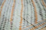 Detailed texture of a distressed Oushak rug with ivory, orange, and charcoal geometric boxes.