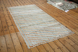 Distressed Oushak runner's corner with diagonal ivory, orange, and charcoal box pattern.