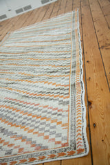 Distressed Turkish Oushak corner with ivory, orange, grey diagonal box pattern and woven border.