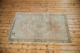 Distressed Oushak rug's lower corner, showing faded floral border and soft grapefruit melon tones.