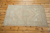Corner of distressed Oushak rug with soft peach, ivory, and beige geometric patterns.