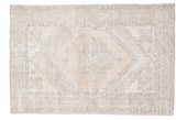 Light and airy distressed Oushak rug with a central medallion in peach, beige, and ivory.