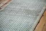 Distressed Oushak rug close-up: faded sea foam green, charcoal, ivory checker pattern.