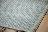 Textured pile of a distressed checker motif Turkish Oushak rug in faded green and ivory.