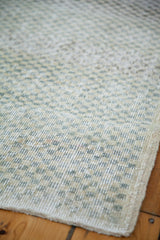 Faded sea foam, ivory, charcoal checker motif on the distressed Oushak rug pile.