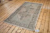 Distressed vintage Oushak rug corner with charcoal geometric floral border and patina peach field.