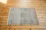Distressed Oushak rug with silver, platinum, and subtle orange floral and lantern motifs.