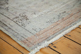 Distressed Oushak rug corner revealing silver, platinum, orange hues, and fringe.