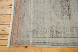 Fringed edge of a distressed vintage Oushak rug, featuring silver and muted orange tones.