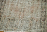 Distressed Oushak rug, faded pile texture ivory, pale peach, charcoal floral motifs, visible fringe.